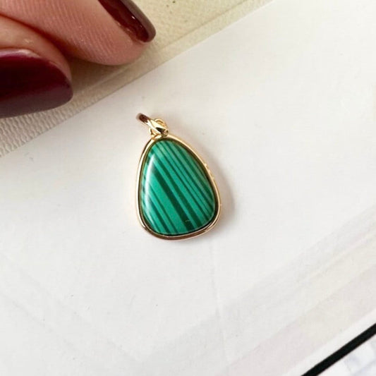 Green malachite gemstone charm on white background
